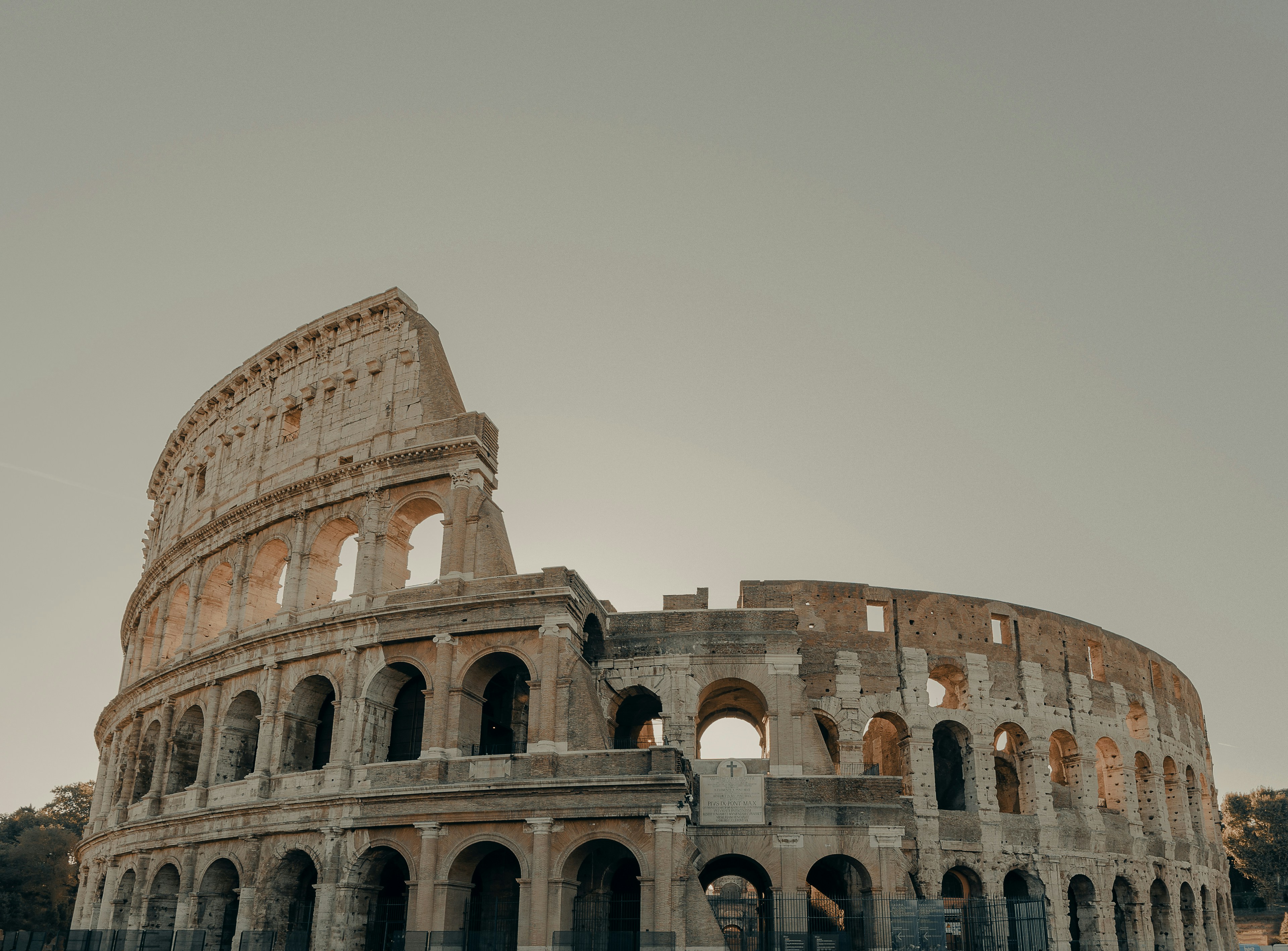 Brown concrete building, or the colosseum, under grey sky in daytime.